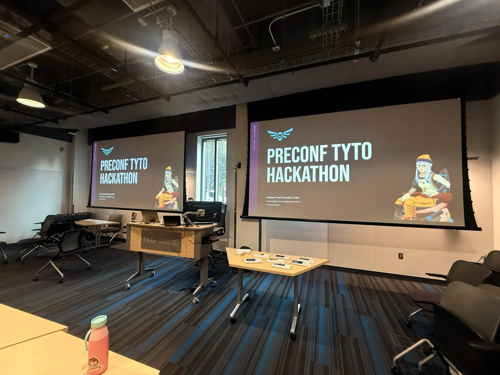 The Duke lecture room before the hackathon began, “Preconf Tyto Hackathon” projected across two large screens above an empty lectern.