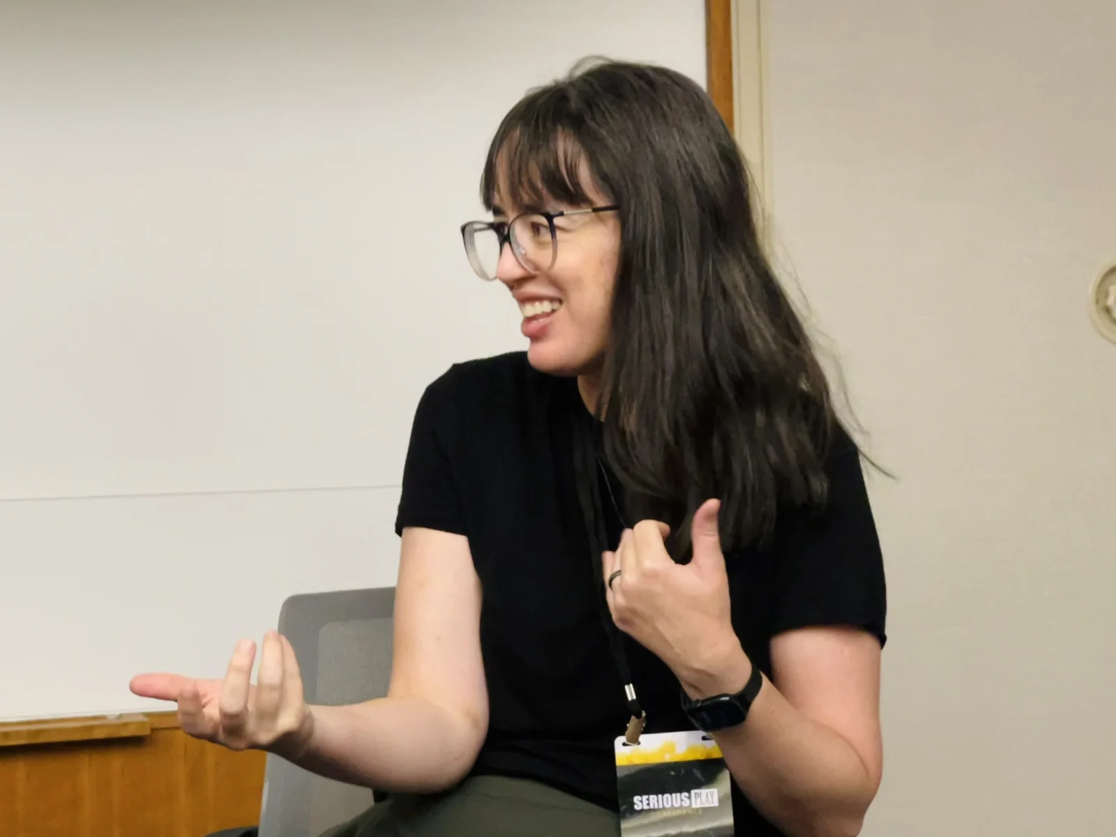 Lindsey Tropf mid-sentence during the panel, both hands raised in a gesture, laughing.