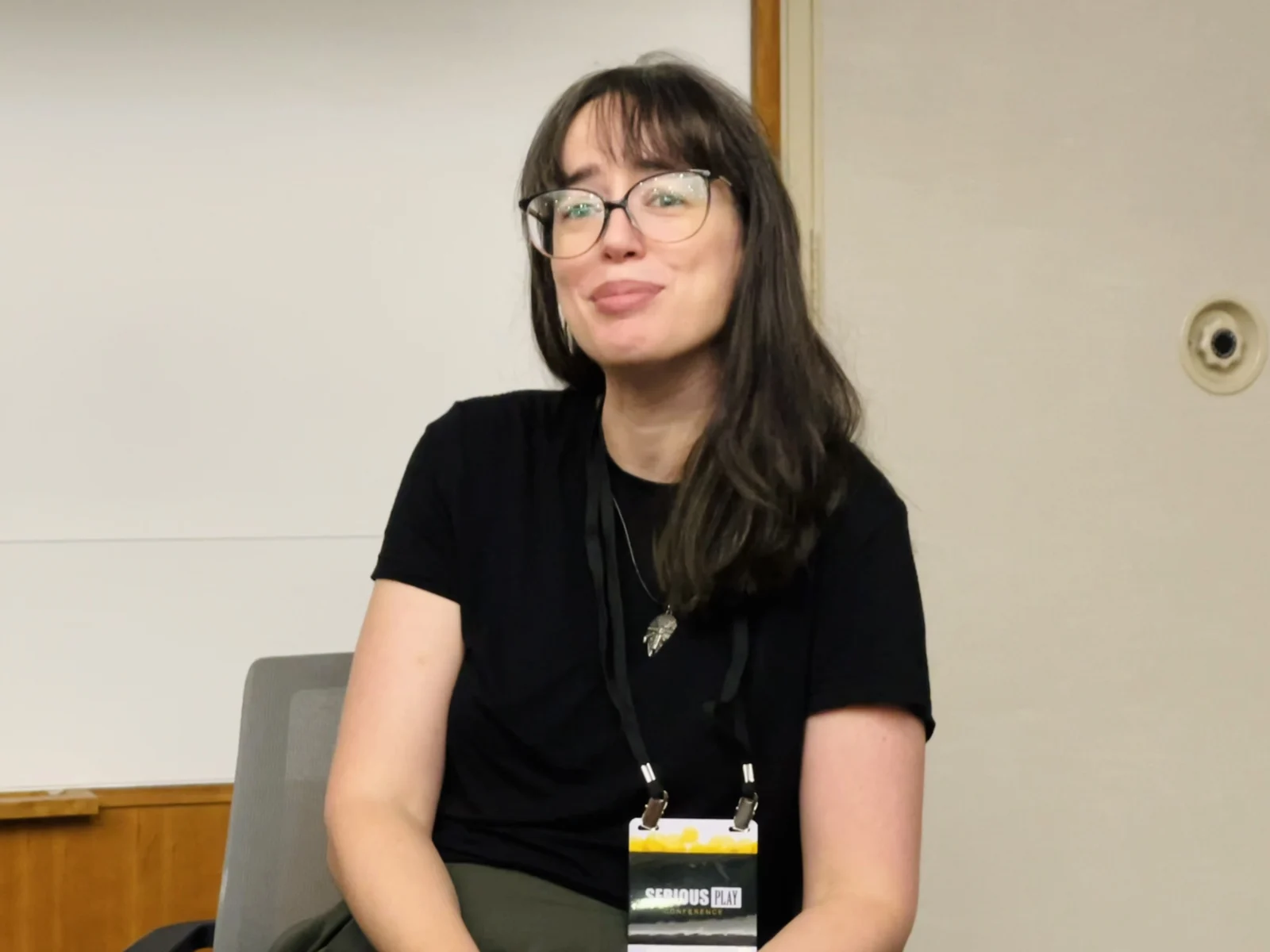 Lindsey Tropf seated during the panel, listening with a wry expression, Serious Play lanyard visible.